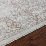 Tapis beige à motifs sur parquet brun.