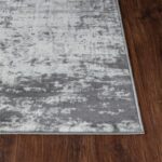 Tapis gris moderne sur parquet brun.