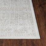 Tapis beige à motifs sur parquet brun.