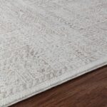 Tapis beige à motifs sur parquet brun.