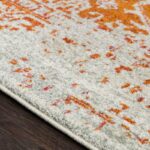 Tapis à motifs oranges sur plancher en bois.