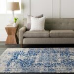 Salon moderne avec canapé gris et tapis bleu.