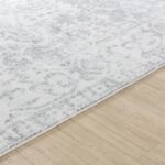 Tapis blanc motif floral sur plancher en bois.