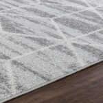 Tapis gris à motifs géométriques sur parquet.