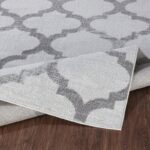 Tapis gris avec motifs géométriques sur parquet.
