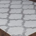 Tapis gris à motifs géométriques sur sol en bois.
