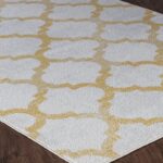 Tapis motif doré géométrique sur plancher en bois.