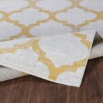 Tapis motif doré sur sol en bois.