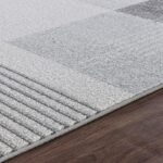 Tapis gris texturé sur plancher en bois.