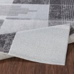 Tapis moderne gris déplié sur sol en bois.