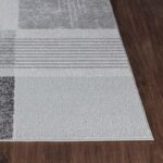 Tapis moderne gris sur parquet brun.