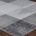 Tapis à motifs géométriques gris sur parquet.