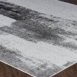 Tapis moderne gris et blanc sur parquet.
