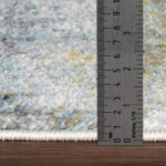 Règle mesurant épaisseur d'un tapis multicolore.