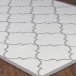 Tapis gris motifs géométriques sur plancher bois.