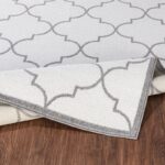 Tapis motif géométrique gris enroulé sur plancher