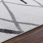 Tapis moderne gris et noir sur parquet.