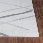Tapis moderne gris et blanc sur plancher bois.