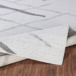 Tapis design gris et blanc sur parquet brun.