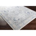 Tapis vintage gris et bleu sur parquet brun.