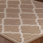 Tapis beige à motifs géométriques sur plancher en bois.
