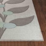 Tapis moderne motifs feuilles sur parquet brun.