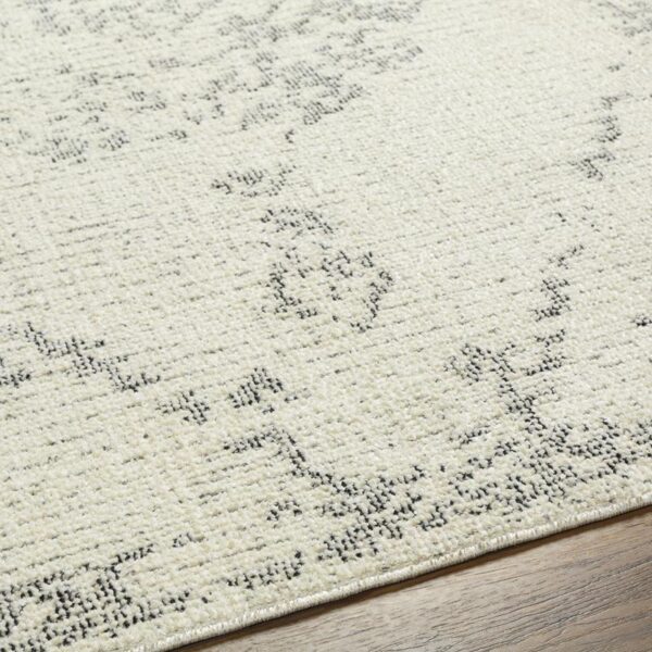 Tapis beige à motifs géométriques noirs.