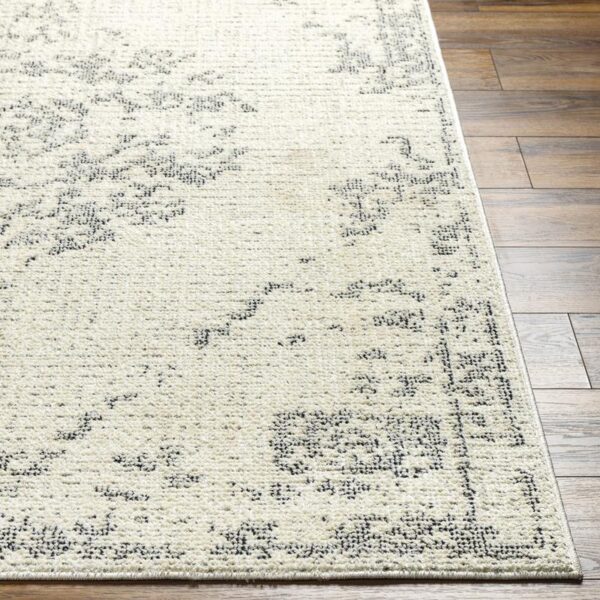 Tapis beige à motifs floraux sur plancher bois.