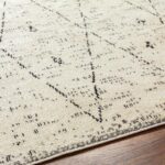 Tapis beige à motifs noirs contemporains sur plancher.