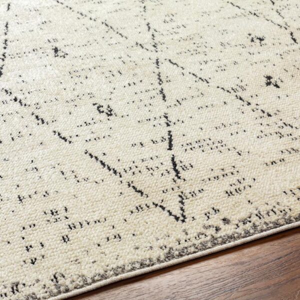 Tapis beige à motifs noirs contemporains sur plancher.