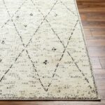 Tapis beige motif berbère sur parquet en bois.