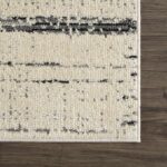 Tapis beige moderne lignes noires sur plancher bois.