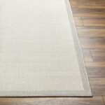 Tapis beige texturé sur parquet en bois.