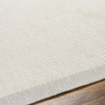 Tapis beige texturé sur plancher en bois.