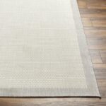 Tapis beige sur sol en parquet brun.