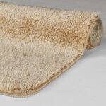 Tapis beige enroulé sur sol clair.