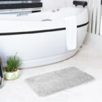 Salle de bains moderne avec baignoire et tapis.