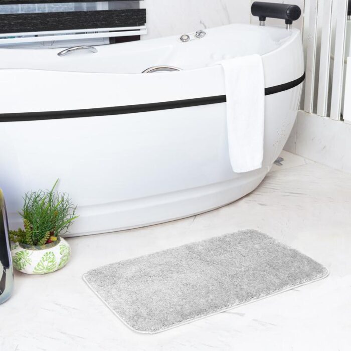 Salle de bains moderne avec baignoire et tapis.