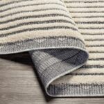 Tapis rayé enroulé sur plancher en bois.