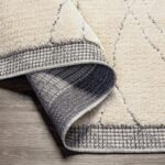 Tapis design beige et gris plié sur sol en bois