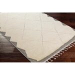 Tapis berbère crème avec motifs géométriques et franges.