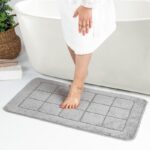 Pied sur tapis de bain gris moderne.