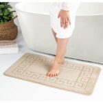 Tapis de bain beige et pieds féminins.