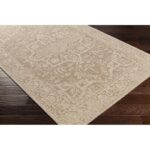 Tapis beige à motifs orientaux sur plancher en bois.