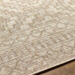 Tapis texturé beige sur plancher en bois.