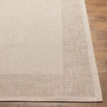 Tapis beige texturé sur plancher en bois.