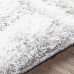 Tapis blanc moelleux sur plancher en bois.