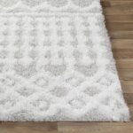 Tapis moelleux blanc sur sol en bois.