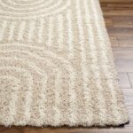 Tapis shaggy crème sur plancher bois.