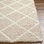 Tapis moelleux beige avec motif géométrique.